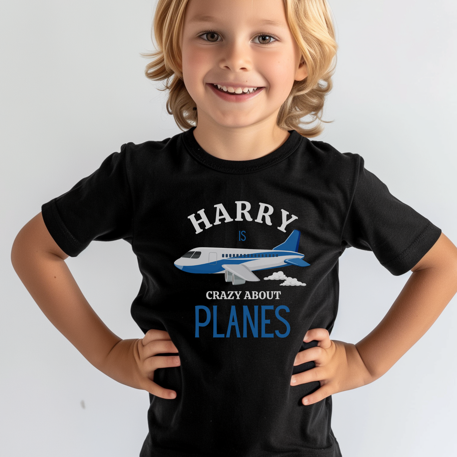 a boy wearing a black t-shirt with a printed design of a plane and the wording harry is crazy about planes 