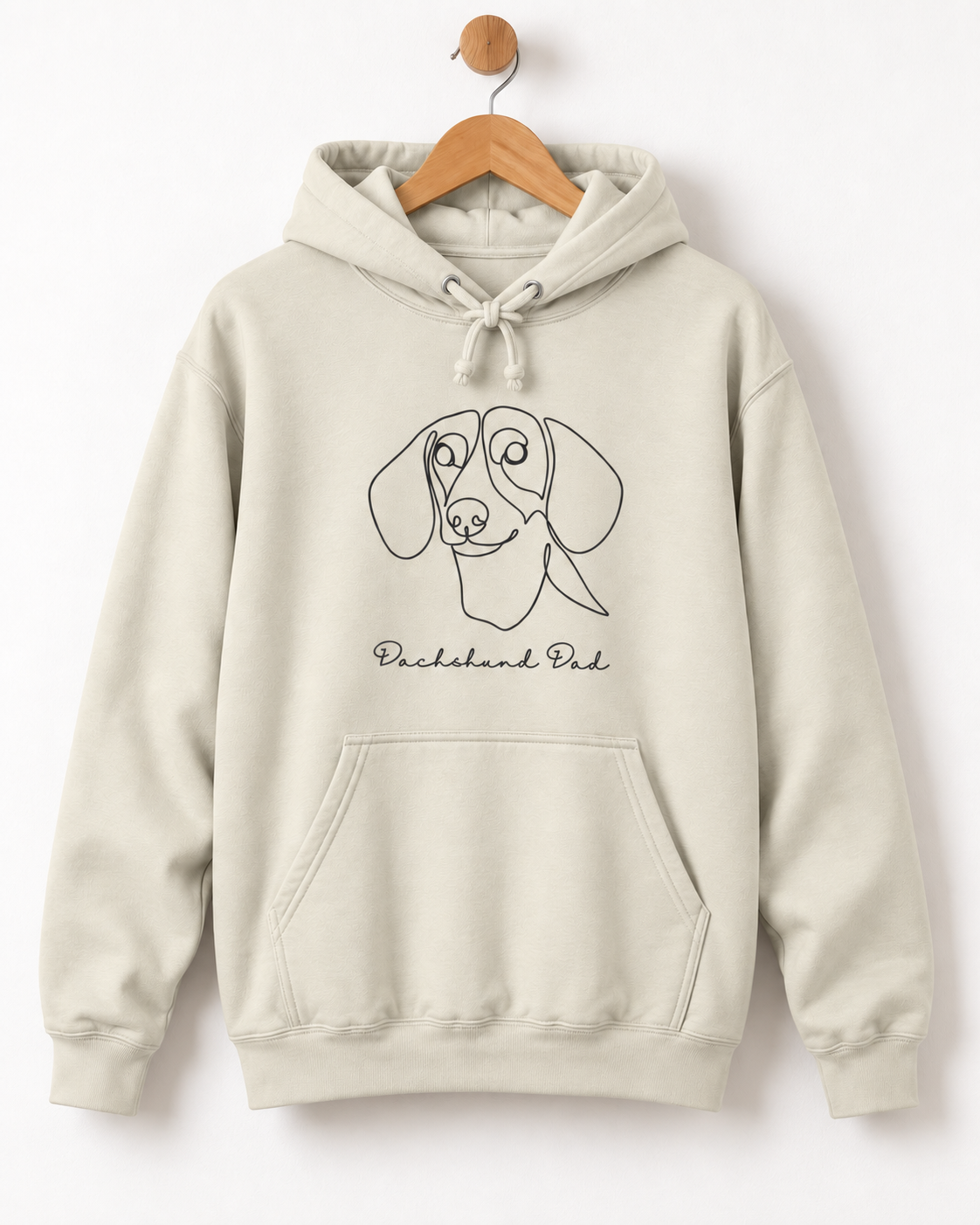 Vanilla milkshake coloured adult hoodie displayed on a wooden hanger, printed with a continuous-line dachshund face and “Dachshund Dad” wording.