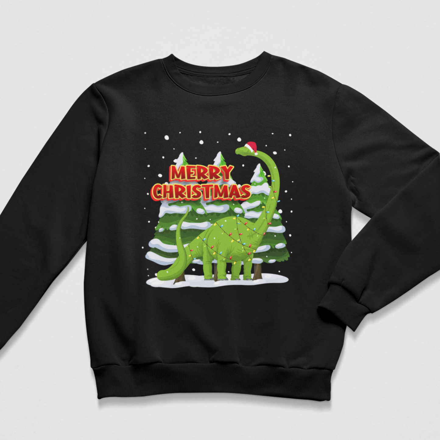 A kids black crewneck sweatshirt featuring a festive Christmas graphic of a green dinosaur standing in front of snow-covered pine trees with the text 'MERRY CHRISTMAS' in red and white.