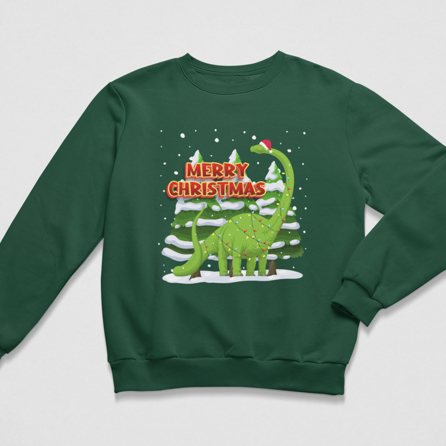 A kids dark green crewneck sweatshirt featuring a festive graphic of a green long-necked dinosaur wearing a Santa hat, standing in front of snowy pine trees with the text 'MERRY CHRISTMAS' in red and white.