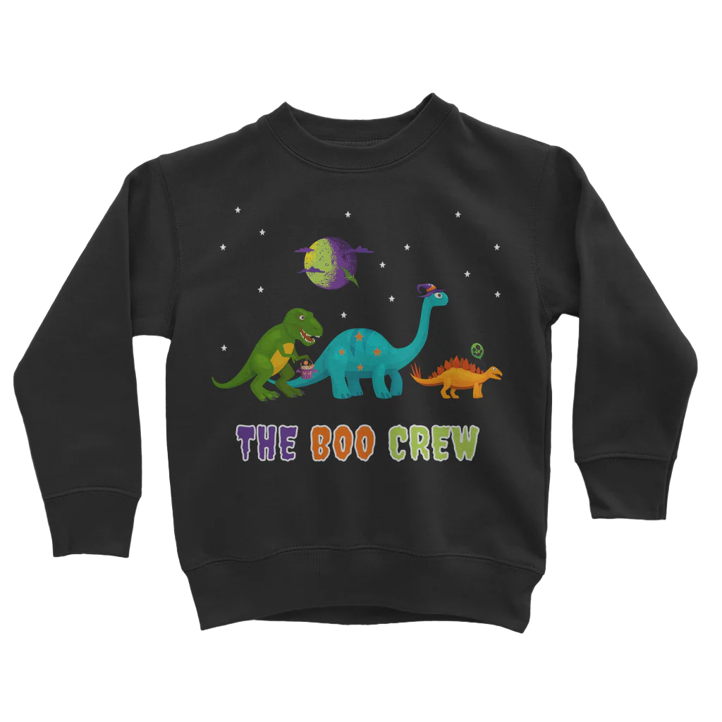 kids black sweatshirt featuring a Halloween-themed dinosaur design. Across the chest iridescent purple, orange, and green lettering, is the phrase "THE BOO CREW". Above this text are three cartoon dinosaurs set against a night sky with small white stars and a stylized full moon with a purple and green landscape.