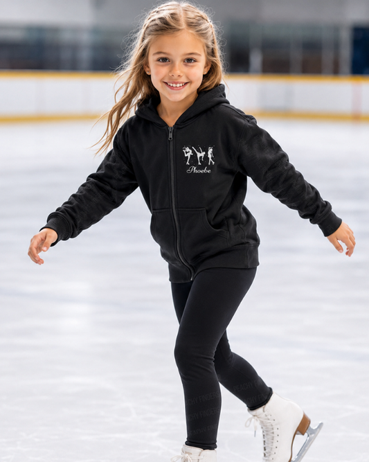 Young girl on a ice rink wearing a black hoodie featuring three white ice skater silhouettes with personalised name on the chest.