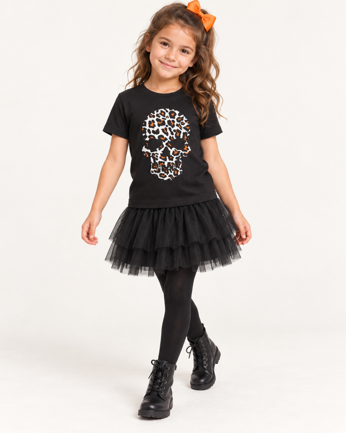 Six-year-old girl wearing a black T-shirt with a white, black and orange leopard-print skull, styled with a black tulle skirt, tights and ankle boots.