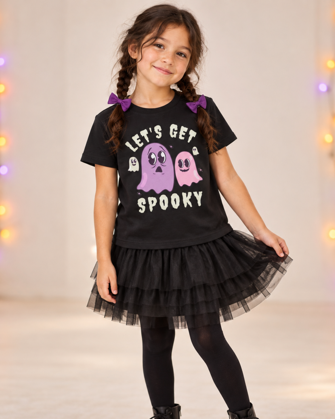 Girl wearing a black Halloween T-shirt with pink and purple ghosts and “Let’s Get Spooky” lettering.