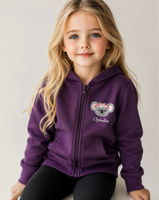 Young girl wearing a purple zip up hoodie with a floral koala design and name underneath design
