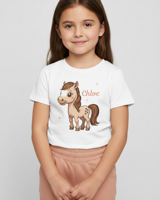 Young girl wearing a personalised white pony T-shirt with name Chloe, paired with dusty peach joggers on a light grey studio background.
