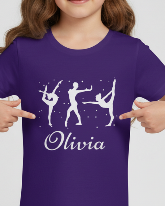 Close-up of personalised purple gymnastics t-shirt showing white gymnast silhouettes and the name “Olivia” in script, model pointing to the design.