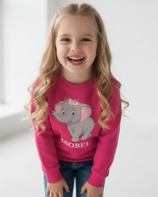 Smiling girl wearing bright pink personalised elephant sweatshirt with floral elephant design and name “Isobel”, studio lifestyle image.