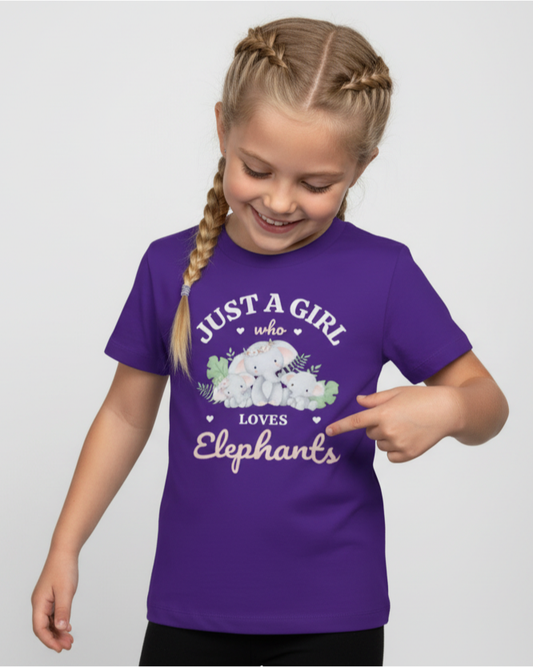 Girl looking down and pointing at the design on a purple “Just a Girl Who Loves Elephants” kids t-shirt, studio photo on a light grey background.