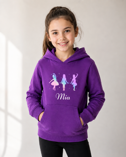 Young girl modelling a black pullover hoodie featuring three colourful dancer silhouettes representing tap, jazz, and ballet styles with a personalised name printed below design