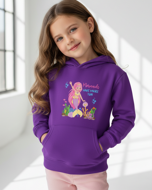 Girl modelling purple mermaid hoodie with colourful underwater graphic and slogan, relaxed studio pose, soft natural light
