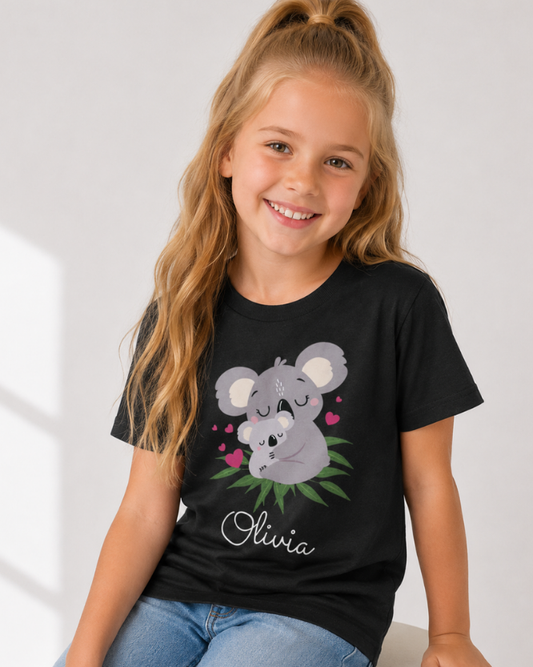 Little girl wearing a black personalised T-shirt with a cute mother and baby koala illustration and her name printed below in white script.