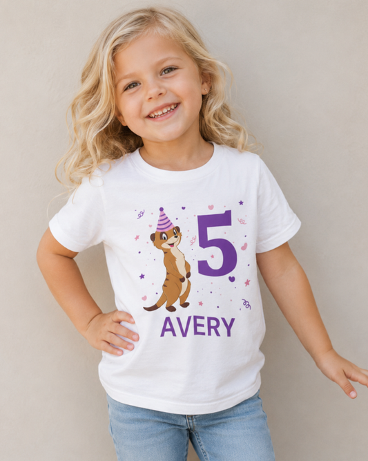 Blonde 4 year old girl wearing personalised white meerkat 5th birthday t-shirt with purple number print and name Avery, posing naturally in studio background
