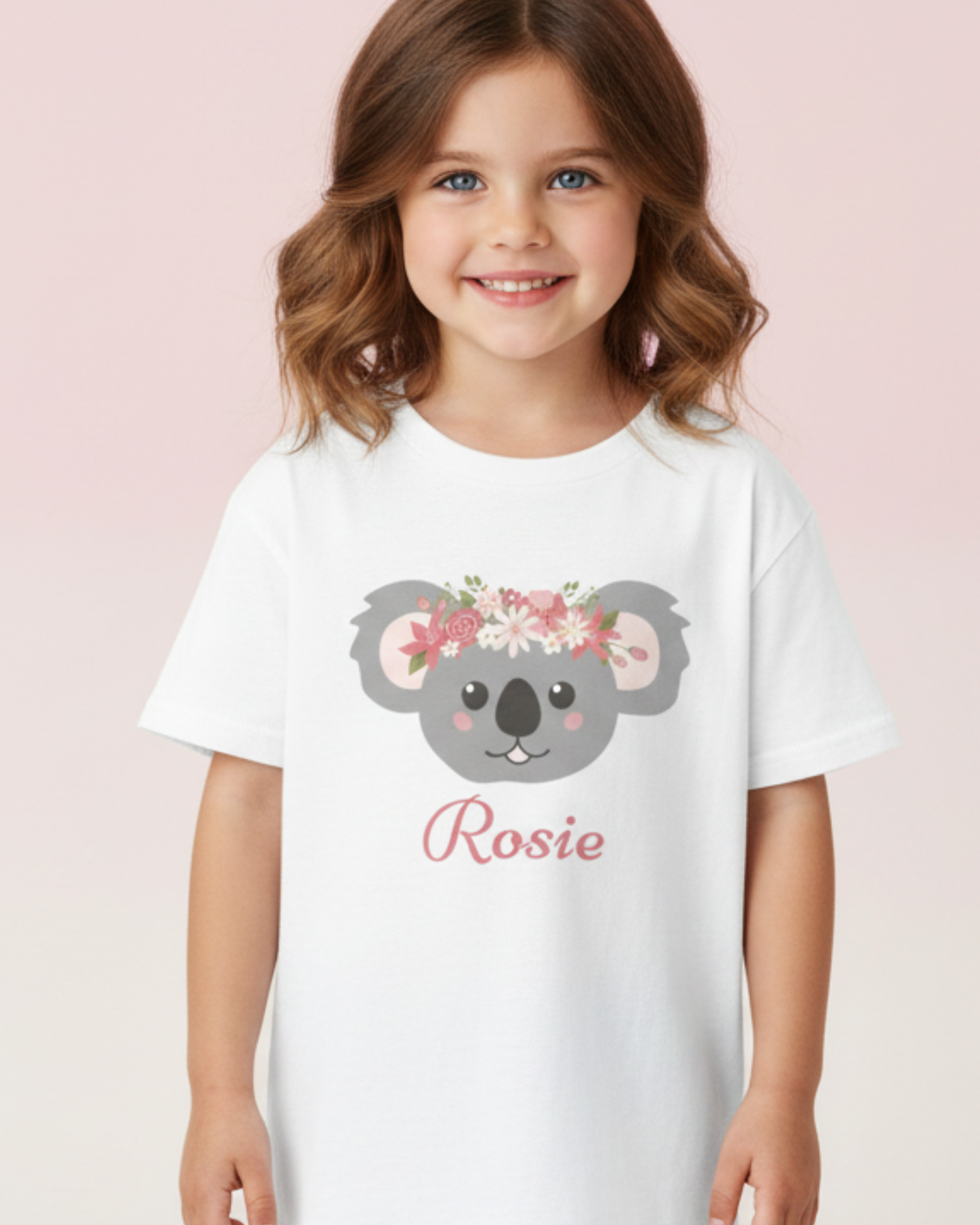 Young girl wearing a personalised floral koala white t-shirt with the name Rosie, studio kids clothing photo with soft pink background
