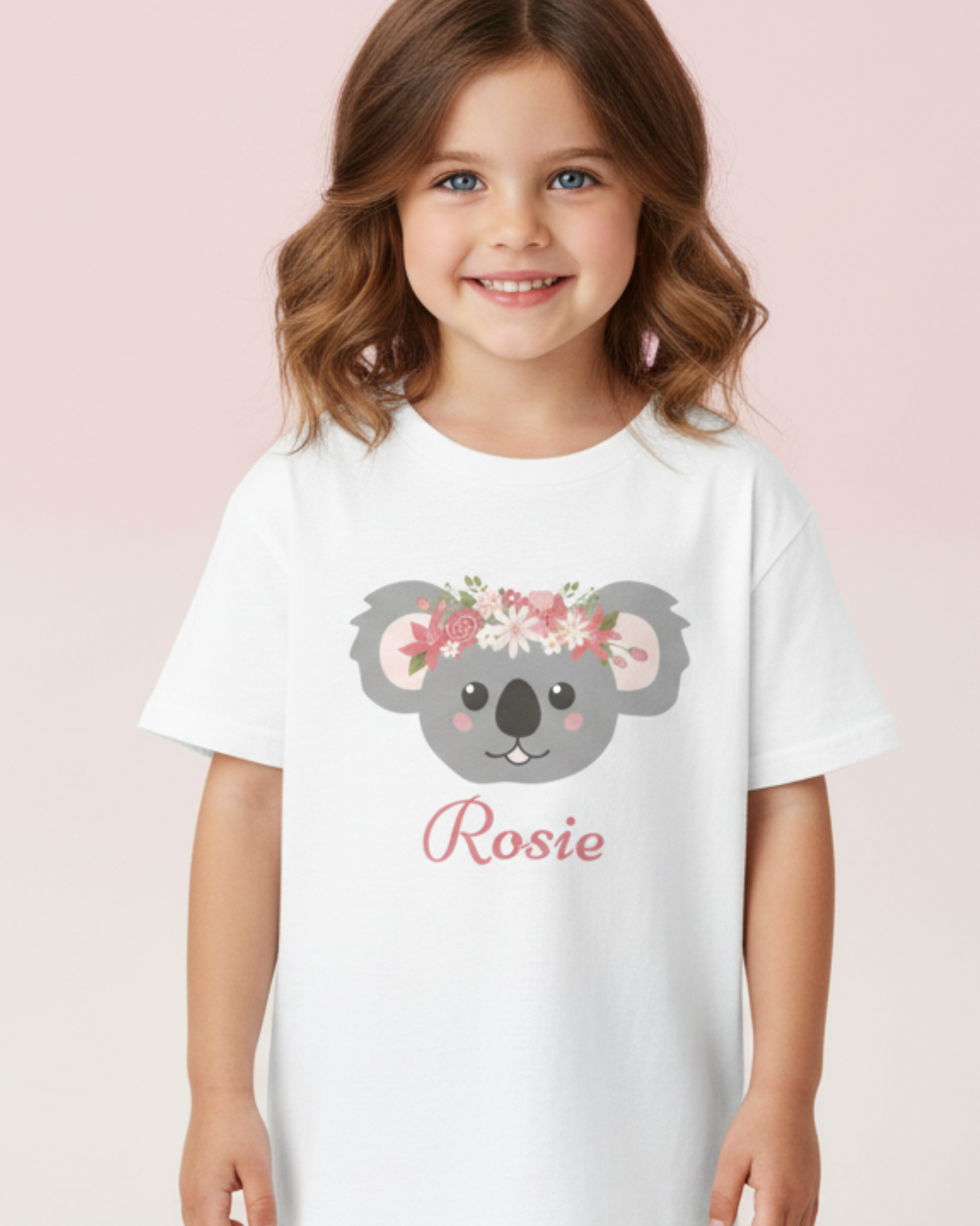 Young girl wearing a personalised floral koala white t-shirt with the name Rosie, studio kids clothing photo with soft pink background