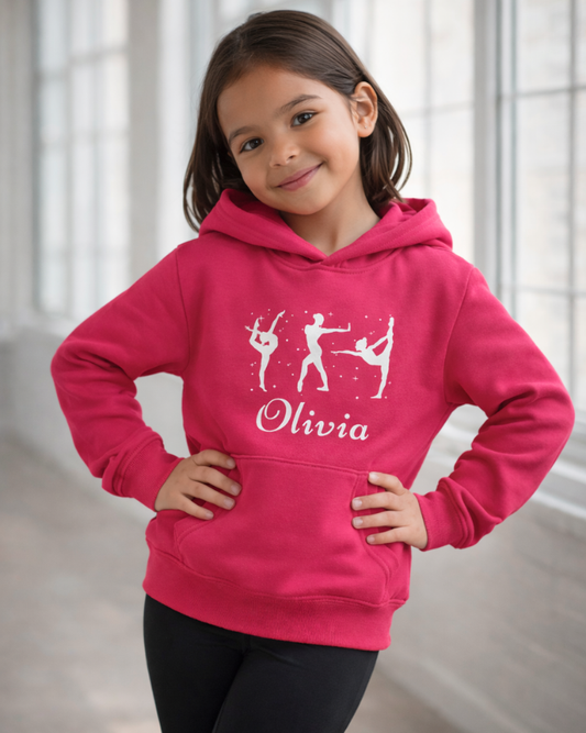 Girl modelling hot pink custom name gymnastics hoodie with gymnast silhouettes and Olivia text, confident pose in a light studio.