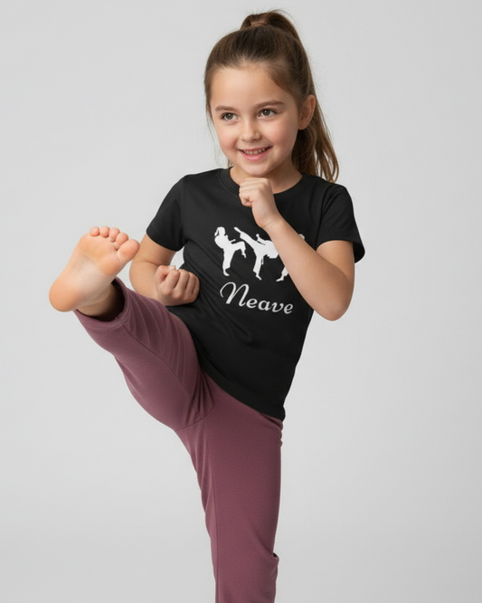 Young girl wearing personalised black karate t-shirt with name Neave performing a high kick in studio