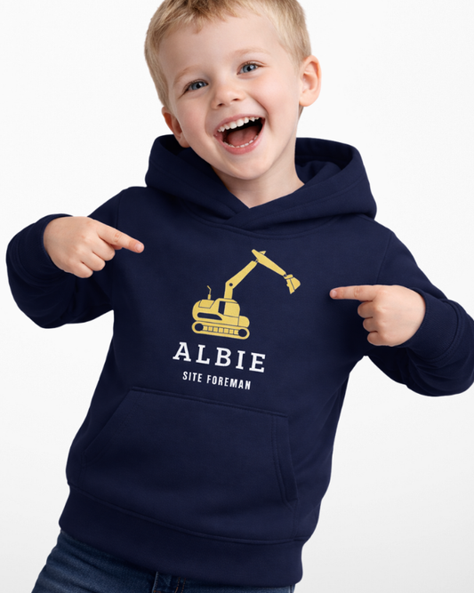 Child modelling navy personalised digger hoodie with custom name and excavator graphic, pointing at design in studio setting.