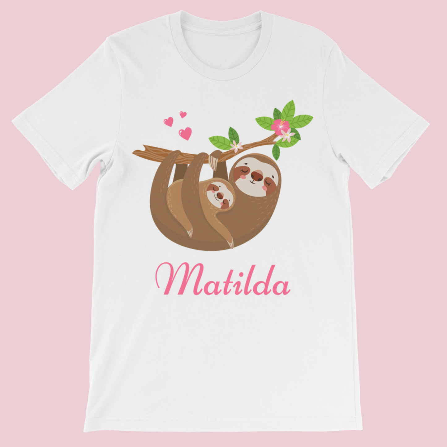 White kids T-shirt on a pink background featuring a mum and baby sloth hanging from a leafy branch with pink hearts and flowers, with the name “Matilda” printed in pink script underneath.