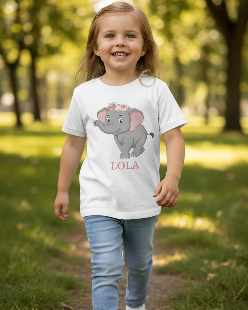 Young girl wearing personalised girls elephant t-shirt in white with floral elephant design and custom name “Lola”, walking outdoors in park.