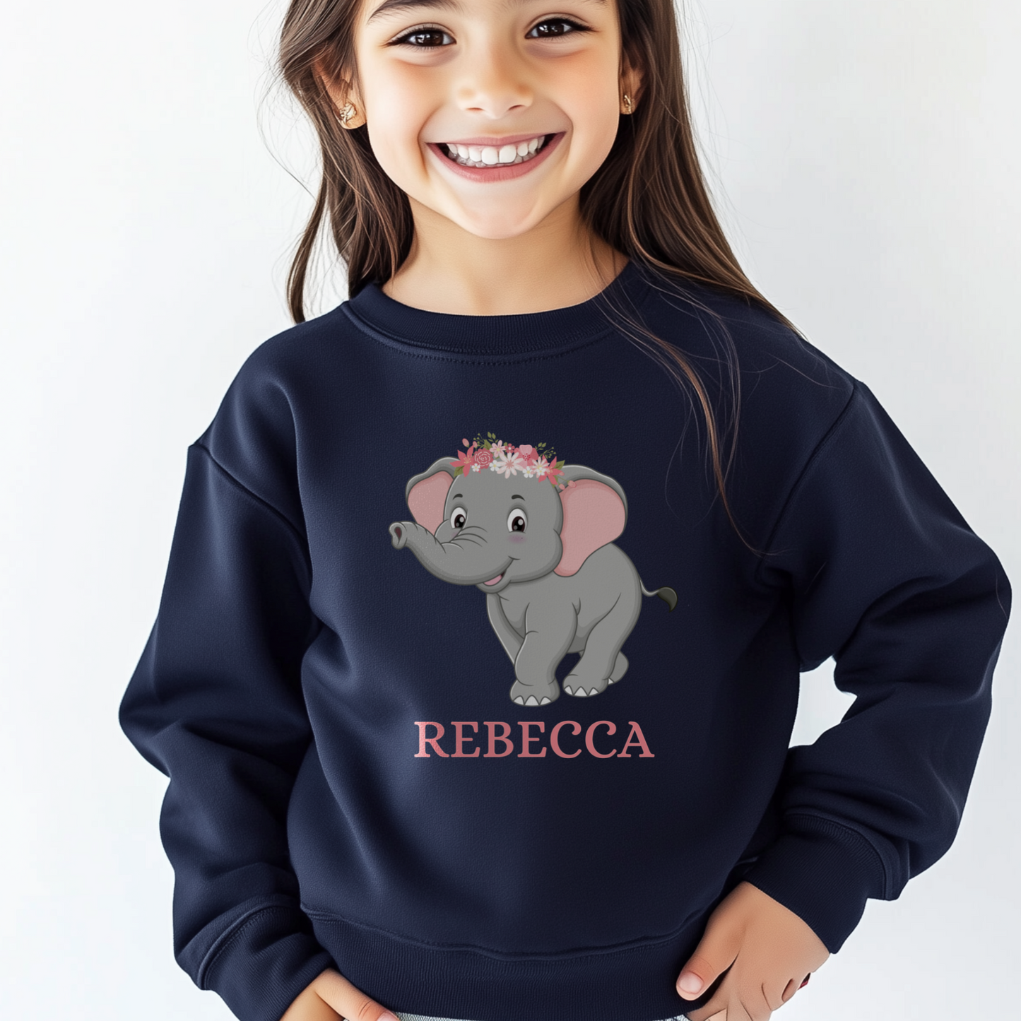 A young girl modelling a navy jumper featuring a cute grey elephant with a flower crown and custom name printed in pink underneath. 