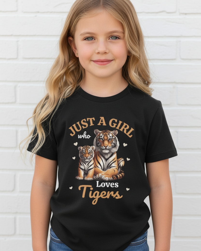 Girl wearing black “Just a Girl Who Loves Tigers” kids t-shirt with tiger and cub graphic, white brick background