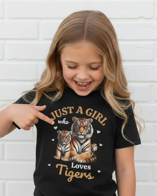 Kids black tiger graphic t-shirt “Just a Girl Who Loves Tigers”, child pointing at the tiger print, white brick background