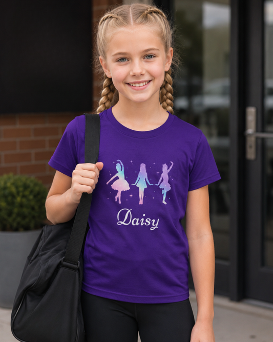 Girl wearing a personalised purple dance t-shirt with pastel ballet tap and jazz dancer design and name Daisy outside a dance studio