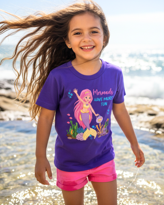 Happy child wearing a purple mermaid graphic t-shirt walking by the sea, “Mermaids Have More Fun” kids summer beach shirt