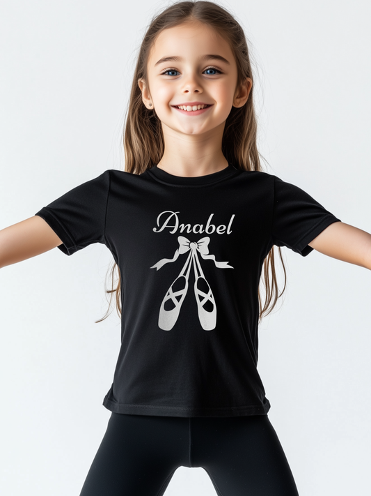 Young wearing a black t-shirt featuring white ballet shoes and bow graphic with personalised name printed on the chest.