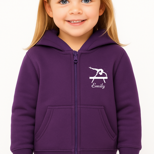 Smiling girl wearing a purple zip-up hoodie with a white balance-beam gymnast and personalised name on the left chest.