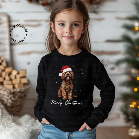 Child wearing a black Christmas-themed sweatshirt with a brown Cockapoo illustration and 'Merry Christmas' text, standing in a festive setting.