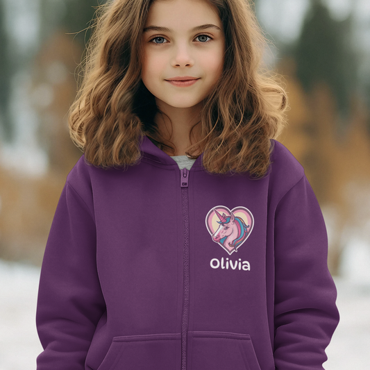 Girl wearing a purple zip hoodie with a unicorn inside a pastel heart and the name “Olivia” printed on the front.