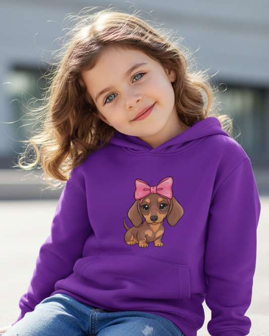 Little girl wears a purple hoodie with a cartoon dachshund wearing a pink bow - outdoor, lifestyle product image