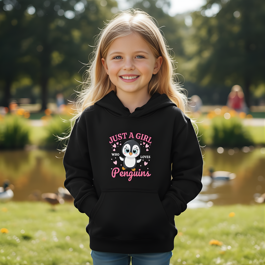 Young girl wearing a black hoodie with a penguin design and text, standing outdoors by a pond.