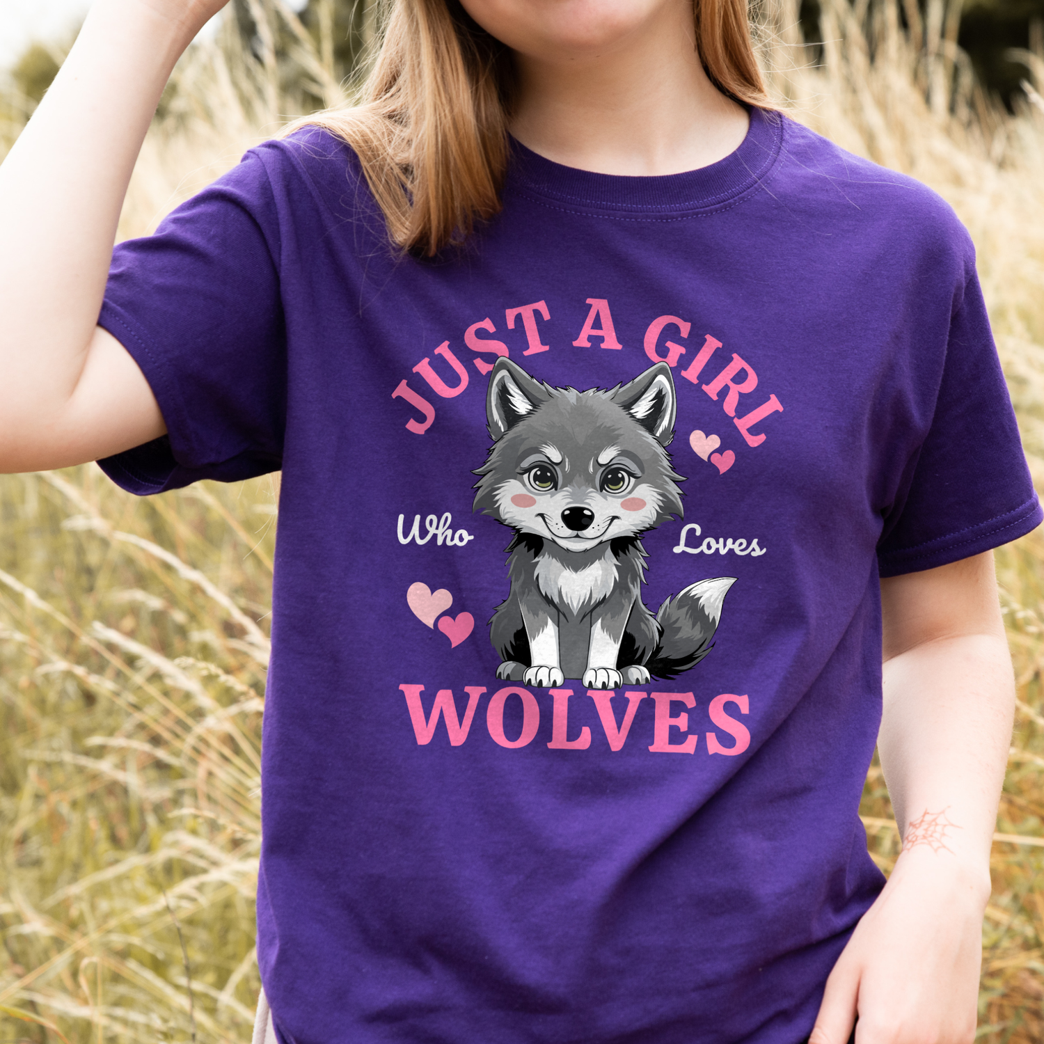 Girl standing in a field wearing a purple “Just A Girl Who Loves Wolves” T-shirt with a cute grey wolf pup and pink hearts, kids wolf tee ages 3–13.
