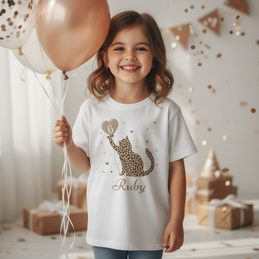 Girl wearing personalised leopard print cat birthday t-shirt with name and age, holding balloons