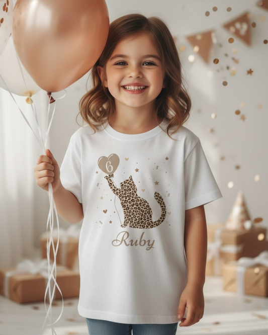 Girl wearing personalised leopard print cat birthday t-shirt with name and age, holding balloons