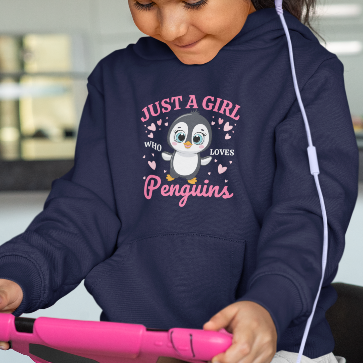 Little girl wears a navy hoodie with cartoon penguin  with pink hearts and 'Just a Girl Who Loves Penguins' text.