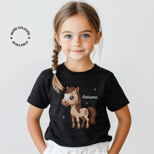 Young girl wearing a black t-shirt with personalised name and cute cartoon brown pony print