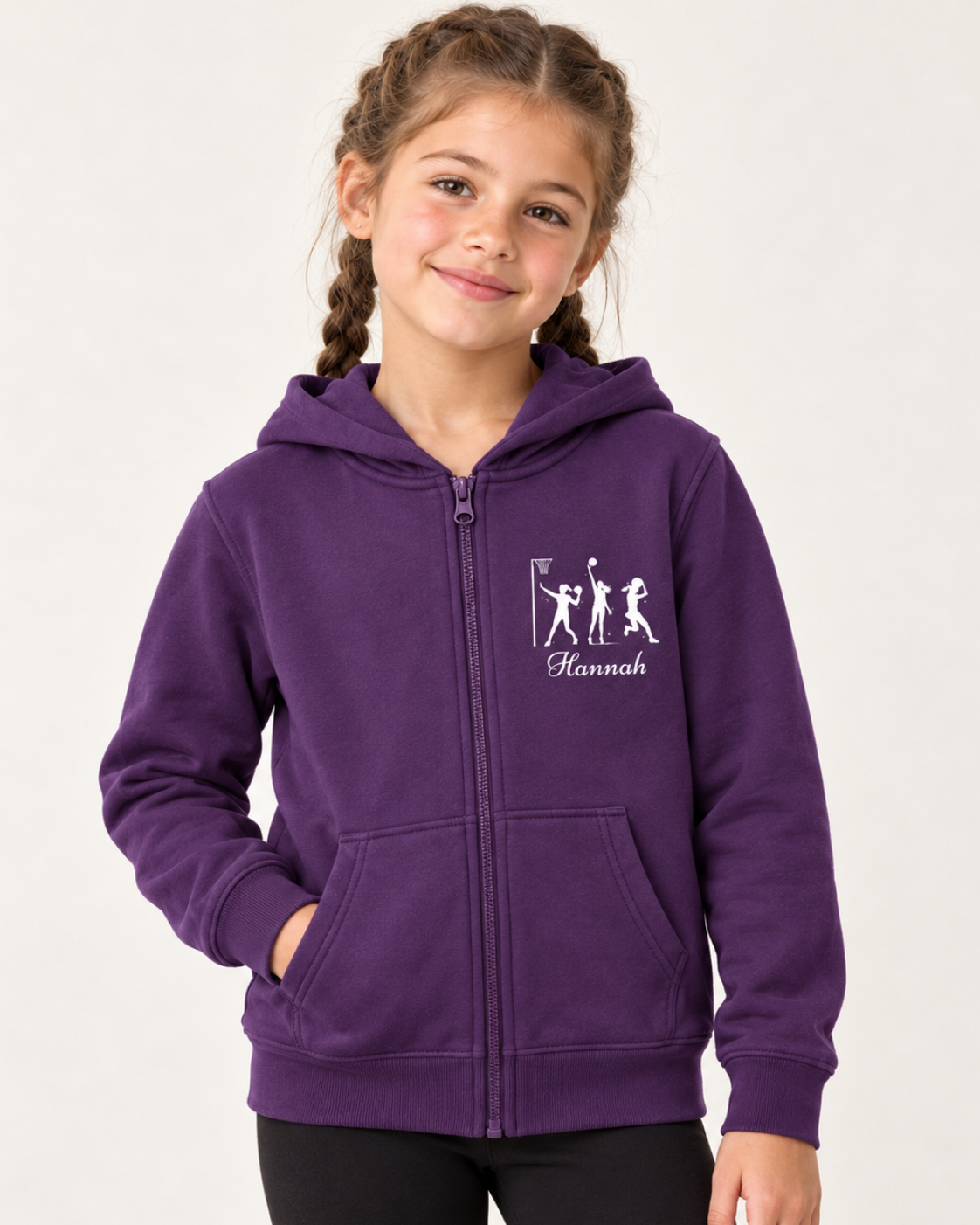 Girl with French plaits wearing a purple personalised netball zip hoodie and black leggings in a bright studio.