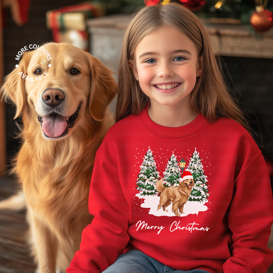 A little girl wearing a red sweatshirt featuring an image of a Golden Retriever and Christmas trees, sitting next to an actual Golden Retriever. Both are looking at the camera.