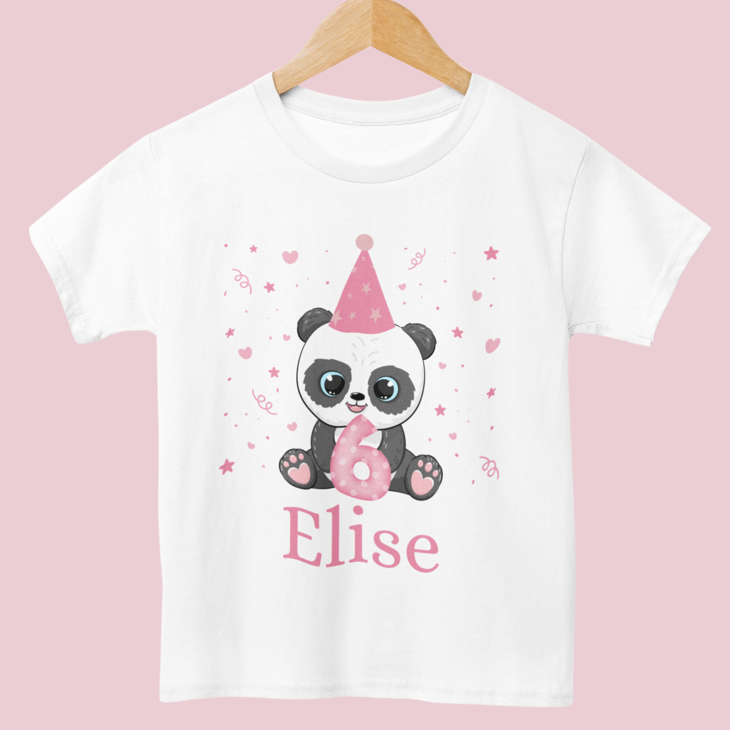 White cotton girls birthday t-shirt featuring a cute panda in a pink party hat holding a number with confetti, stars and hearts around, styled on a wooden hanger