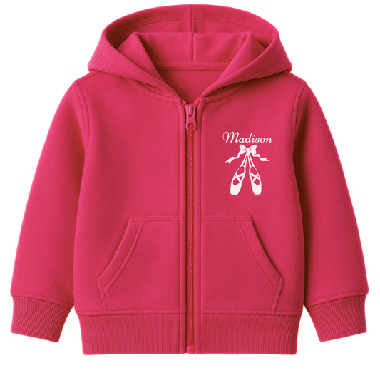 Girls hot pink zip hoodie featuring a graphic print of white ballet shoes and ribbon design with a custom name printed on the left side of the chest