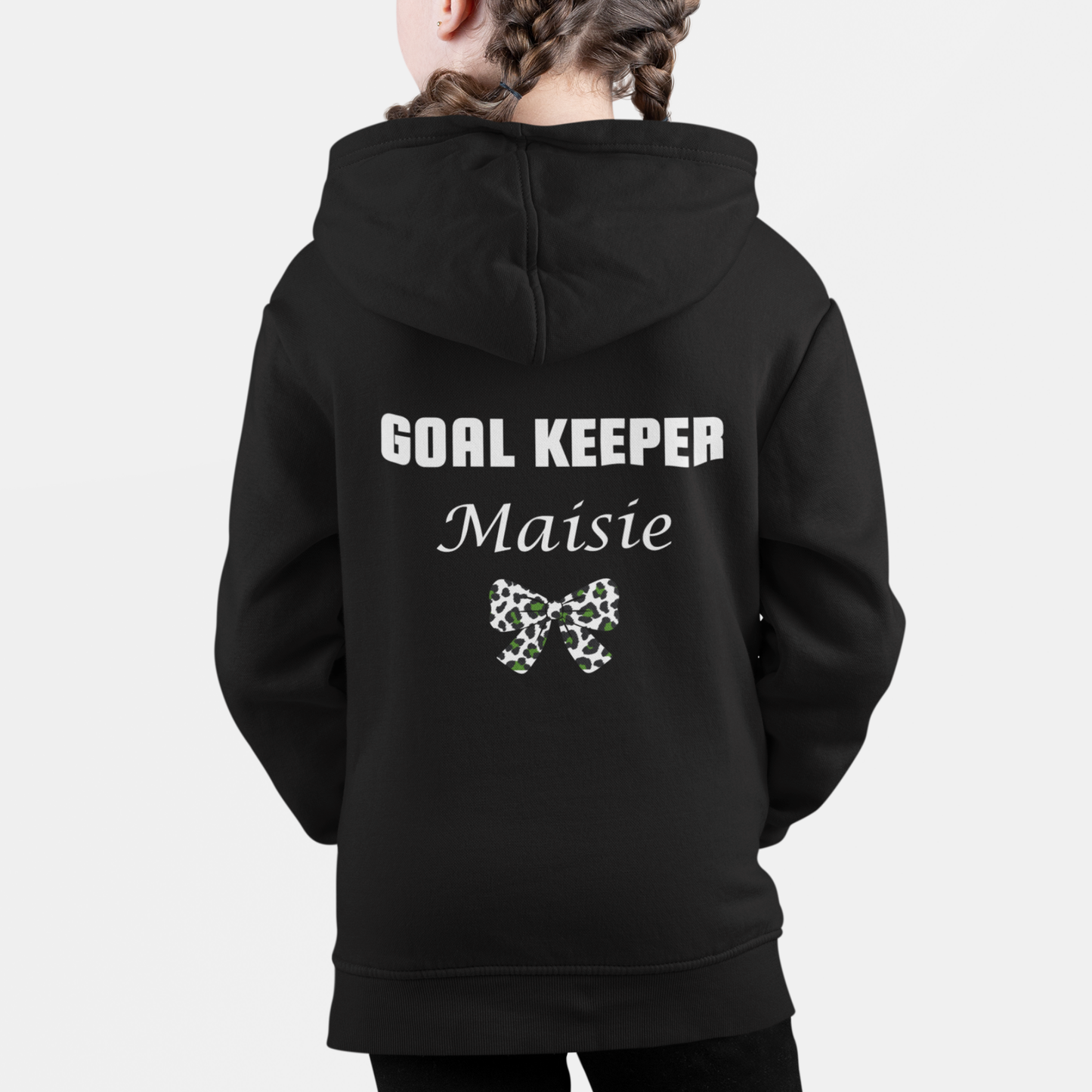 Girl wearing a black personalised football zip hoodie with “Goal Keeper Maisie” printed on the back and a leopard print bow design.