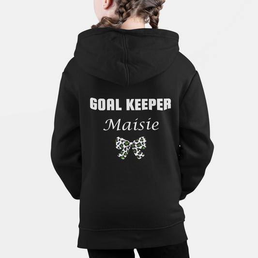 Girl wearing a black personalised football zip hoodie with “Goal Keeper Maisie” printed on the back and a leopard print bow design.
