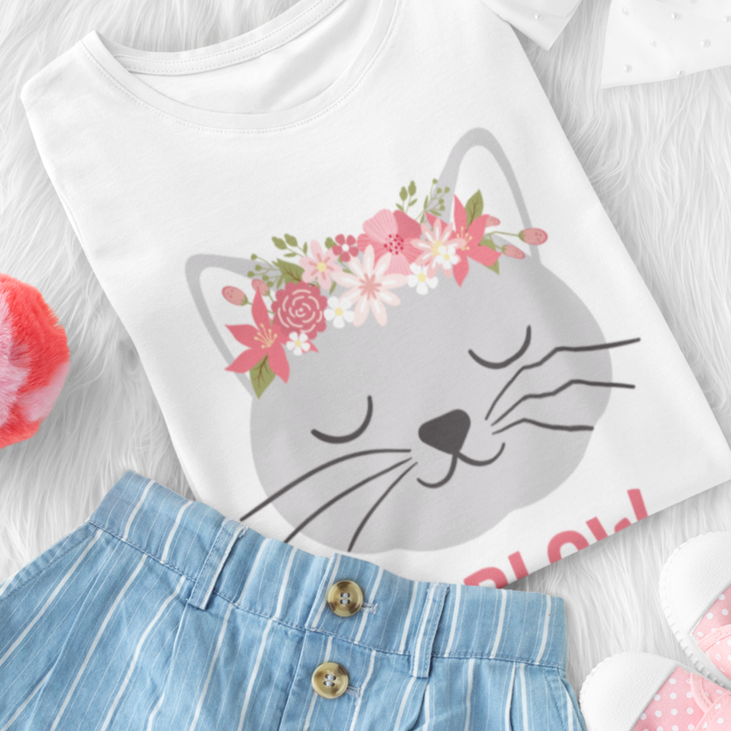 Girls white cotton t-shirt with a cat design and floral accents styled on a white surface with denim shorts.