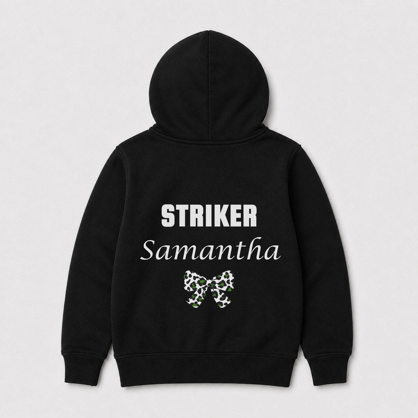 Kids football-themed black zip hoodie shown from the back, featuring the word 'STRIKER' in white block letters, 'Samantha' in white script, and a small green and white bow graphic below. The hoodie is displayed on a light grey background.