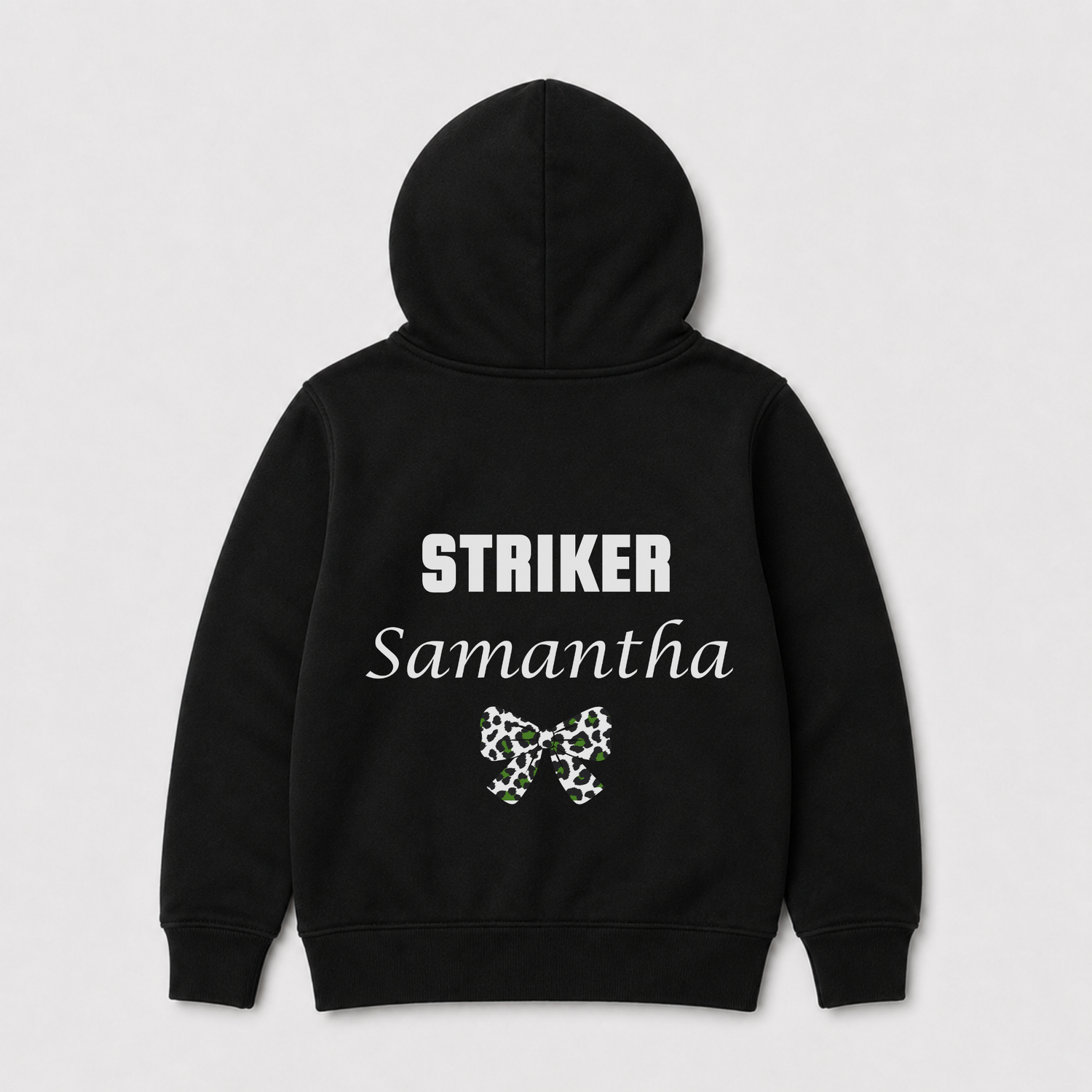 Kids football-themed black zip hoodie shown from the back, featuring the word 'STRIKER' in white block letters, 'Samantha' in white script, and a small green and white bow graphic below. The hoodie is displayed on a light grey background.