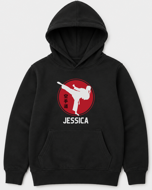 A girls black pullover hoodie with a red circular graphic of a white martial arts kick and the name 'JESSICA' printed in white below it, shown on a light gray background.